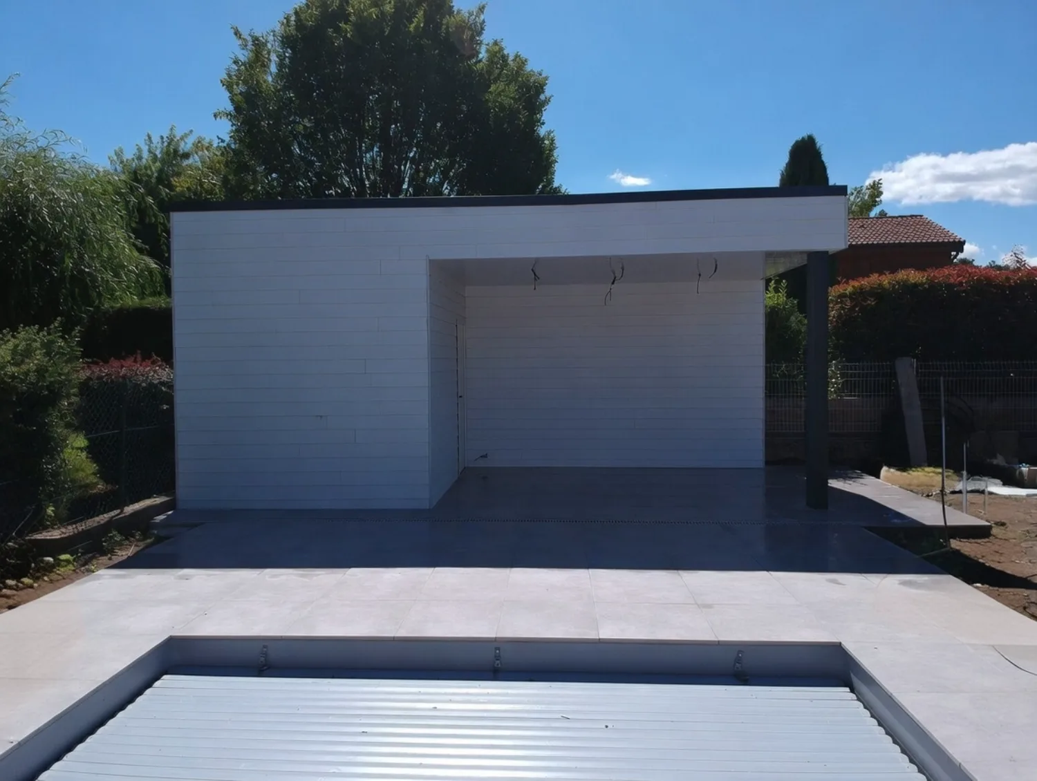 Annexe de jardin en ossature métallique légère à toiture plate au bord d'une piscine