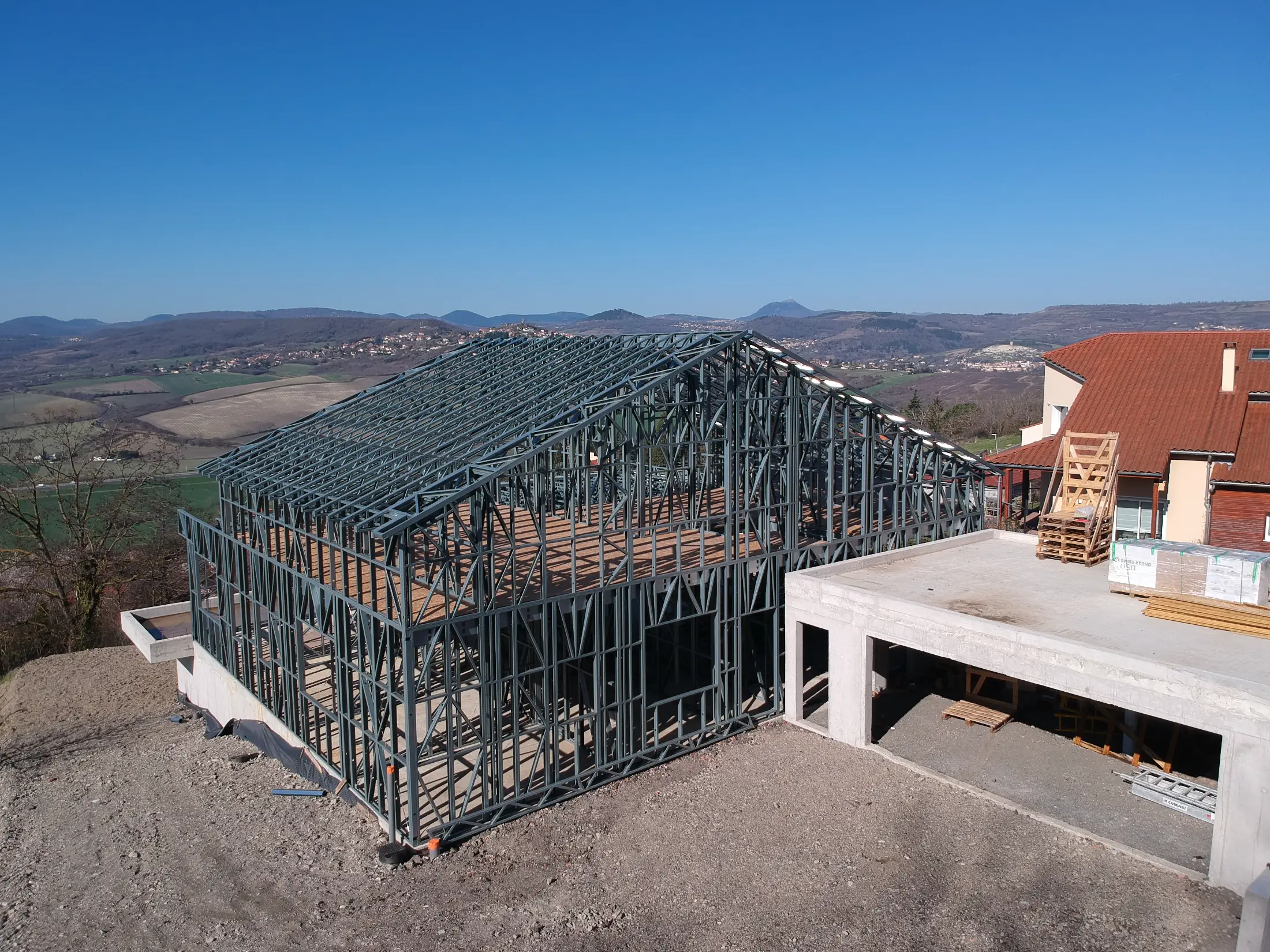 Ossature métallique légère d'une maison individuelle en cours de montage face à la chaîne des Puys