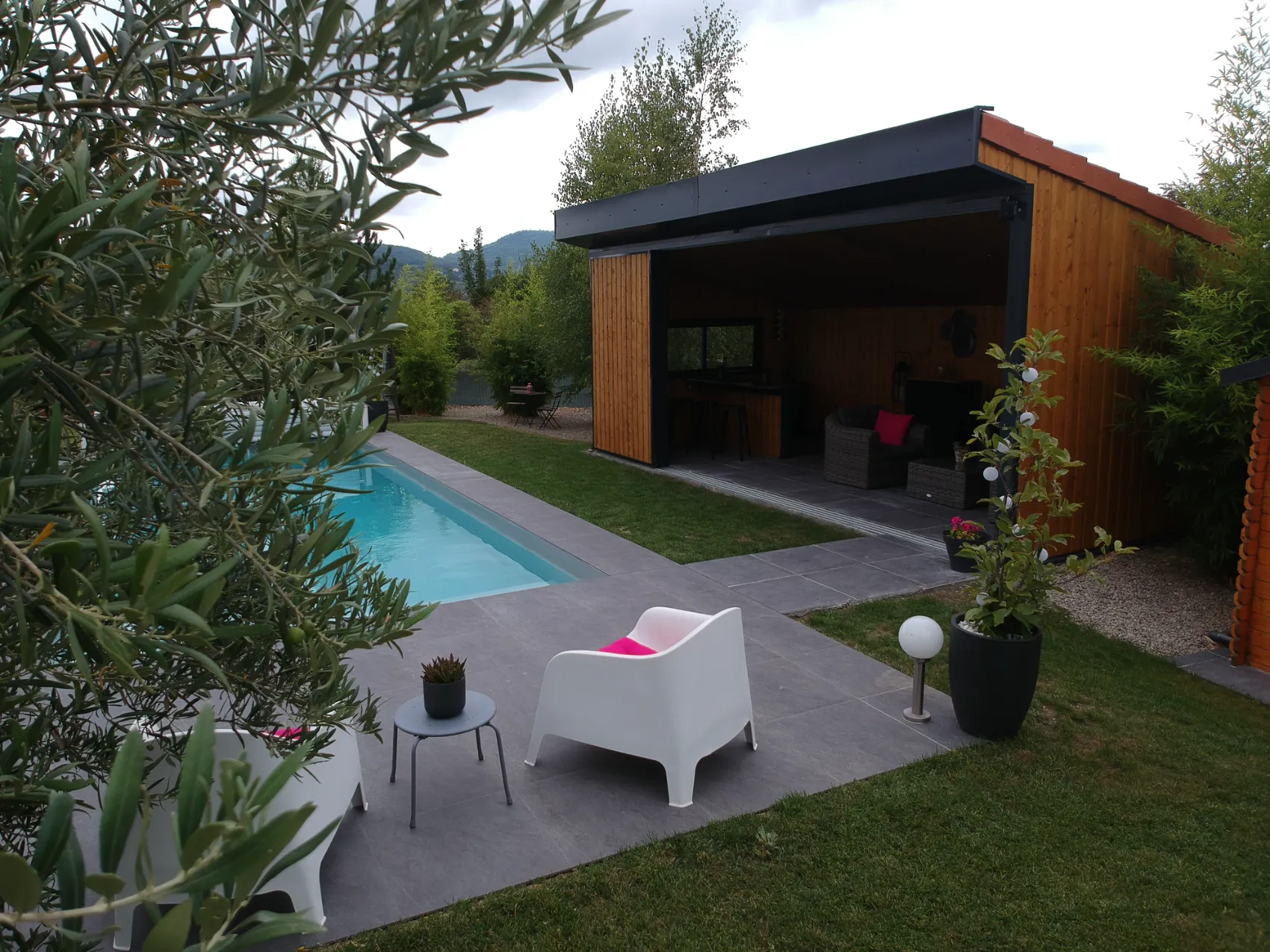 Pool house en ossature métallique avec bardage bois au bord d'une piscine